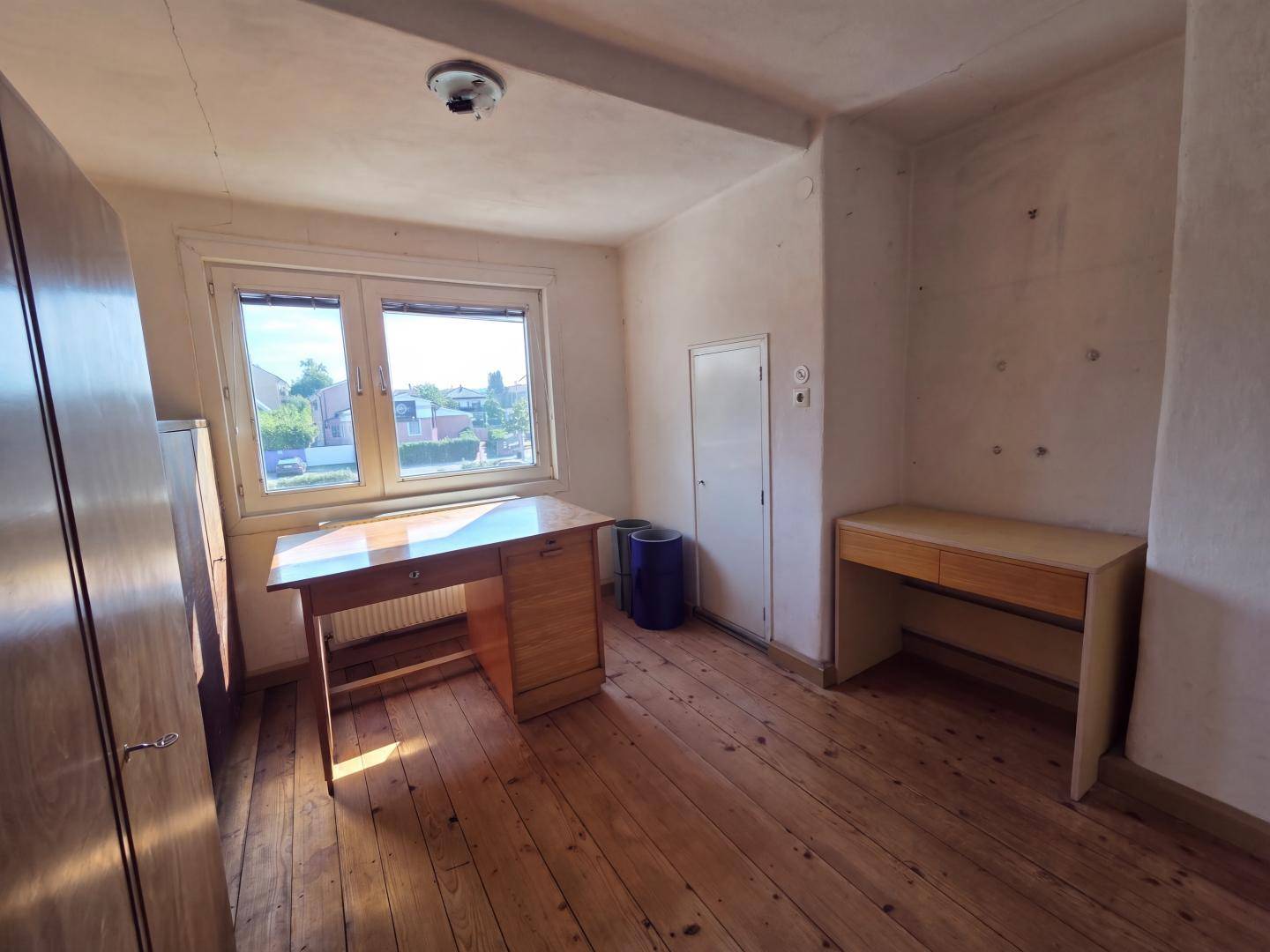 Helles Arbeitszimmer mit zwei Schreibtischen und Dielenboden.