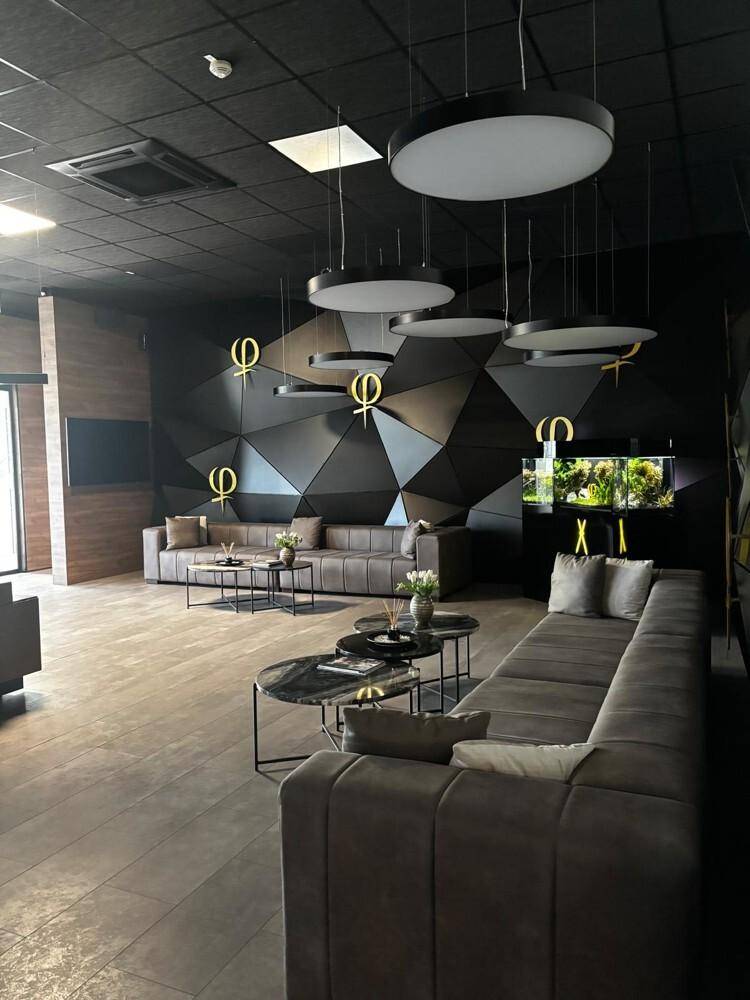 Moderner Loungebereich mit dunklen Wänden, geometrischen Mustern, bequemen Sofas und stilvoller Beleuchtung.