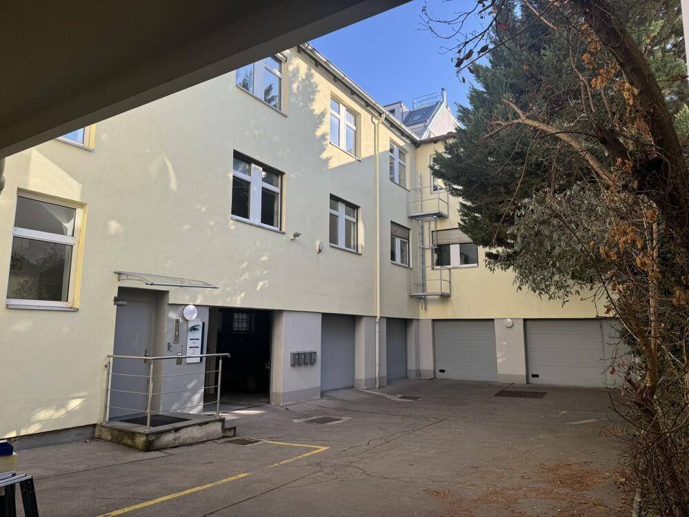 Innenhofansicht des Gebäudes mit mehreren Garagentoren und einem Eingangsbereich.