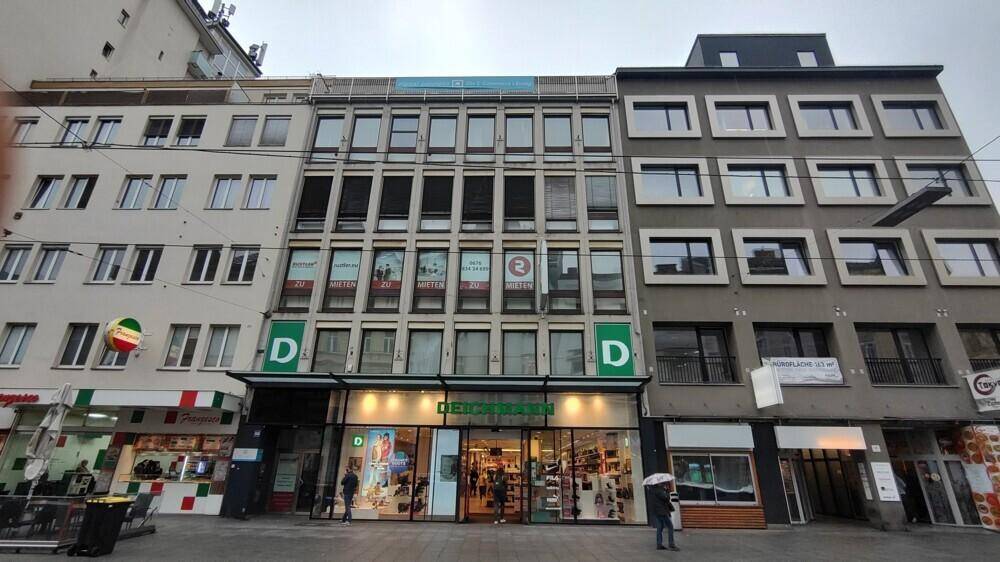 Ansicht der Geschäftsgebäude-Fassade mit mehreren "Zu vermieten"-Schildern und belebter Straße.