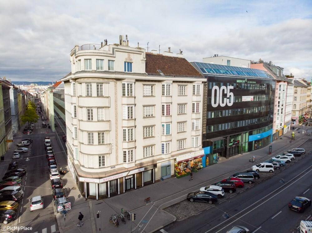 Luftaufnahme einer Stadtstraße mit einem historischen Gebäude und einem modernen Bürokomplex.