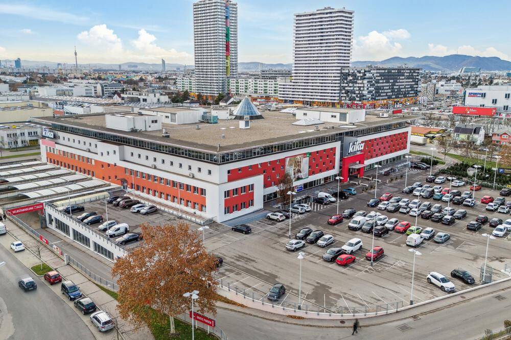 Weitläufige Ansicht des Kika Möbelhauses mit Parkplätzen und markanten Hochhäusern in der städtischen Umgebung.