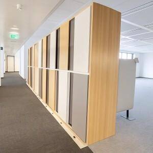 Langer Bürogang mit modularen Trennwänden und Teppichboden in einem modernen Bürogebäude.