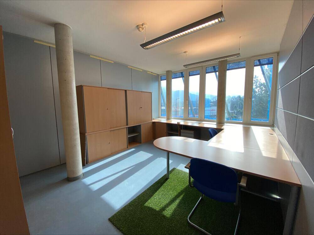 Geräumiges Büro mit U-förmigem Schreibtisch, Säule und Fenstern mit Ausblick, sehr hell.