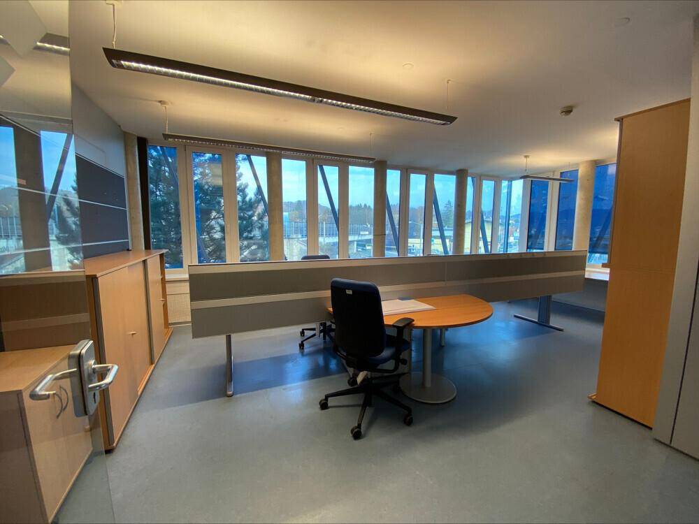 Offener Bürobereich mit Arbeitsplätzen, Trennwänden und Fenstern mit Weitblick.