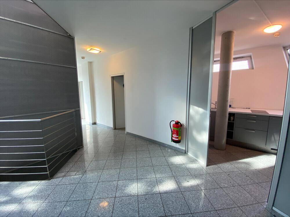 Flur mit gefliestem Boden, Feuerlöscher und Blick auf eine kleine Küchenzeile.