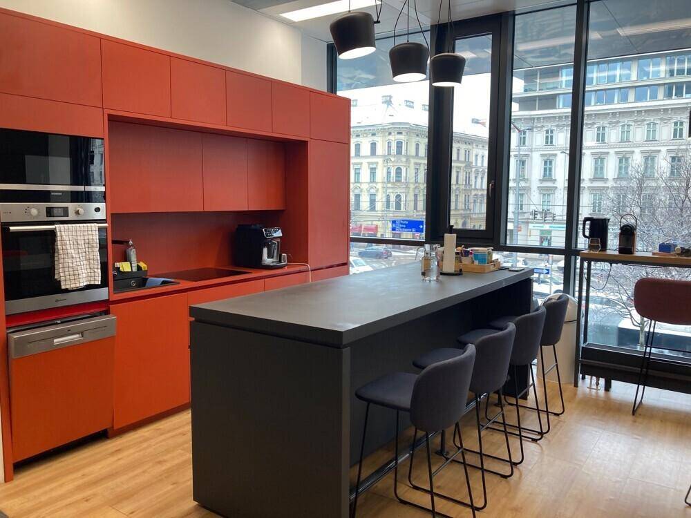 Moderne Küche mit leuchtend orangefarbenen Schränken, integrierten Geräten und einer Kücheninsel.