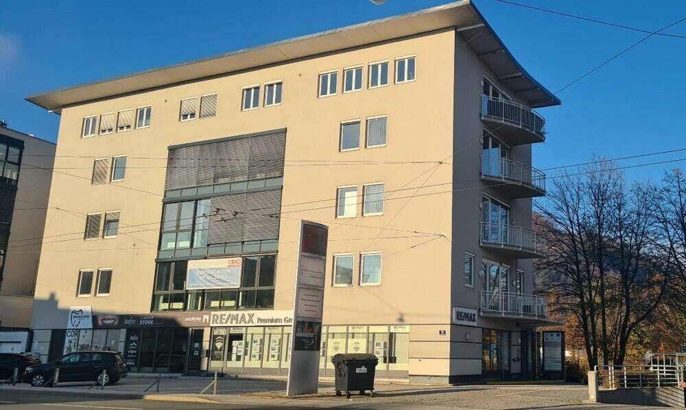 Modernes Geschäftsgebäude mit beiger Fassade, großen Glasflächen und mehreren Balkonen.