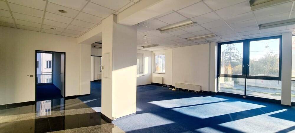 Großes Büro mit Teppich- und Steinboden, Säulen und weitreichenden Fenstern für Tageslicht.
