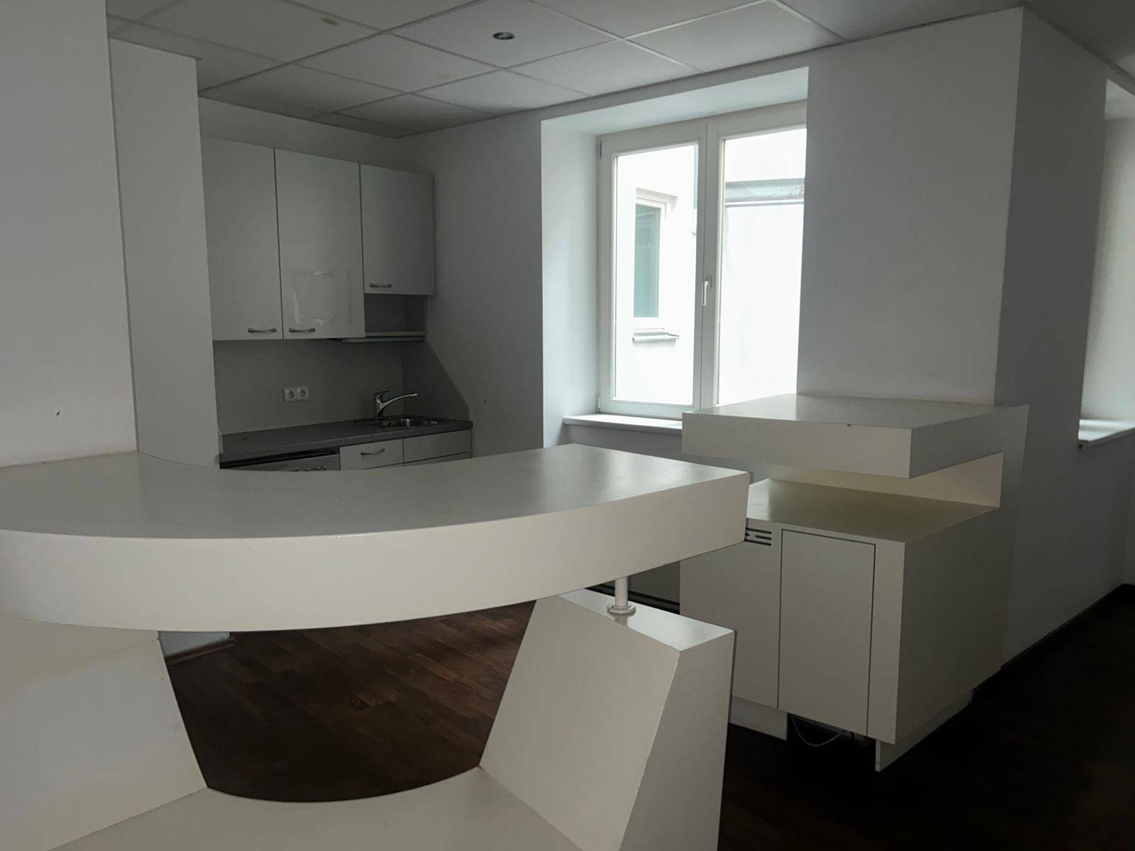 Moderne Küchenzeile mit weißer Theke und Schränken, ideal für einen Essbereich mit Fenster.
