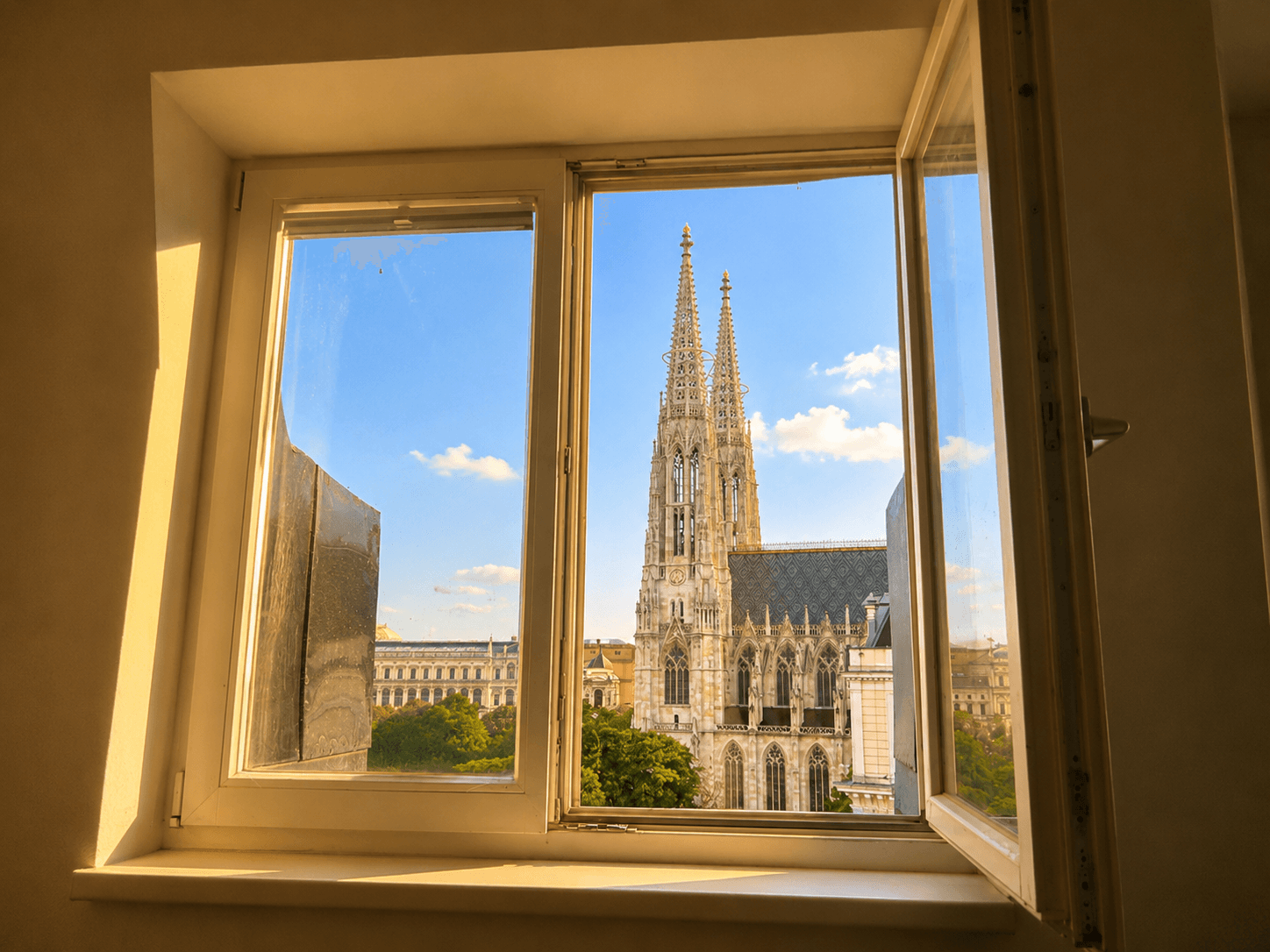 Offenes Fenster mit beeindruckendem Blick auf eine historische Kirche und die Stadt, durchflutet von natürlichem Licht.