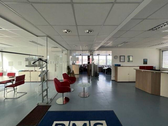 Geräumiges Büro mit Empfangstheke, Glasabtrennungen und Sitzgelegenheiten in leuchtendem Rot.