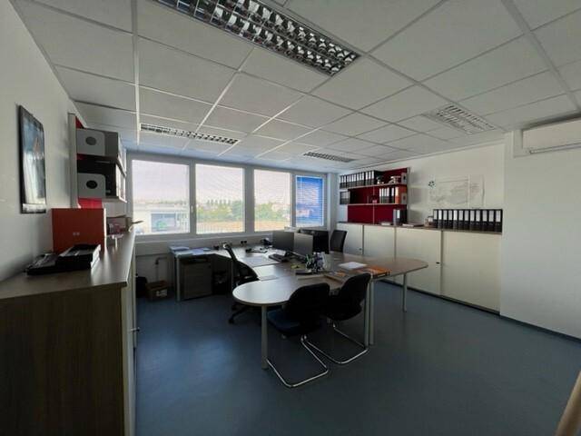 Helles Einzelbüro mit Schreibtisch, Bürostühlen und viel Stauraum an den Wänden.