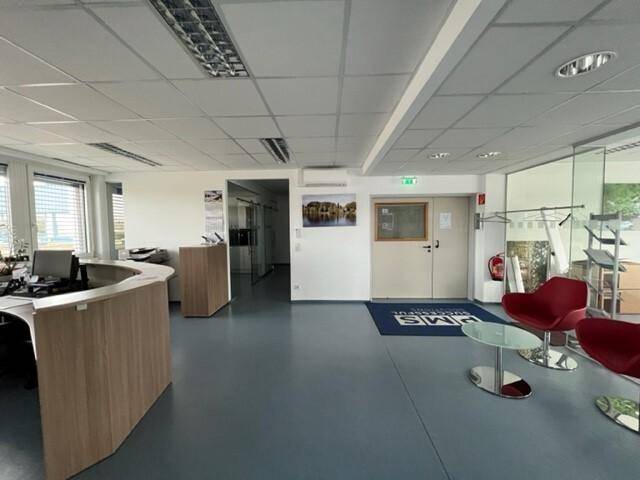 Empfangsbereich eines Büros mit moderner Theke, Sitzgelegenheiten und Zugang zu weiteren Räumen.