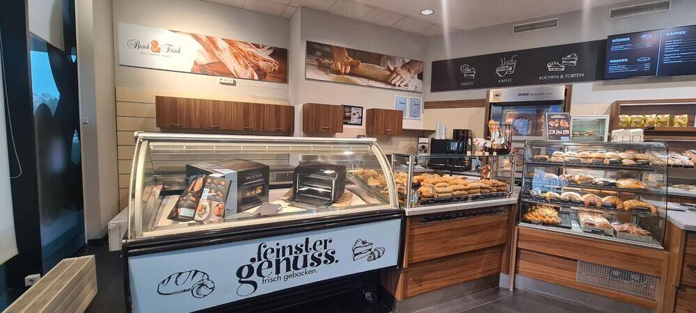 Innenansicht einer Bäckerei mit Auslagen voller Backwaren und Holzvertäfelung an den Wänden.