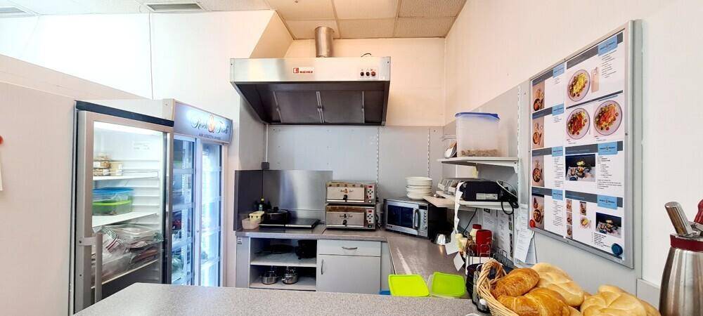 Professionelle Küche mit Edelstahlgeräten, Dunstabzugshaube und Kühlschrank, bereit für den Betrieb.