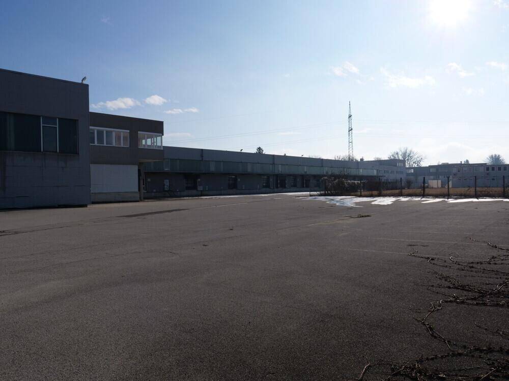 Weitläufiger Außenbereich eines Industriegebäudes mit großem asphaltierten Platz und klarem Himmel.