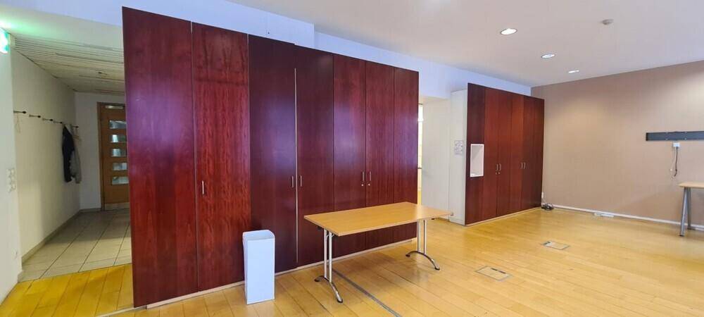 Geräumiger Bürobereich mit dunklen Holzschränken, Holzboden und einem einfachen Tisch.