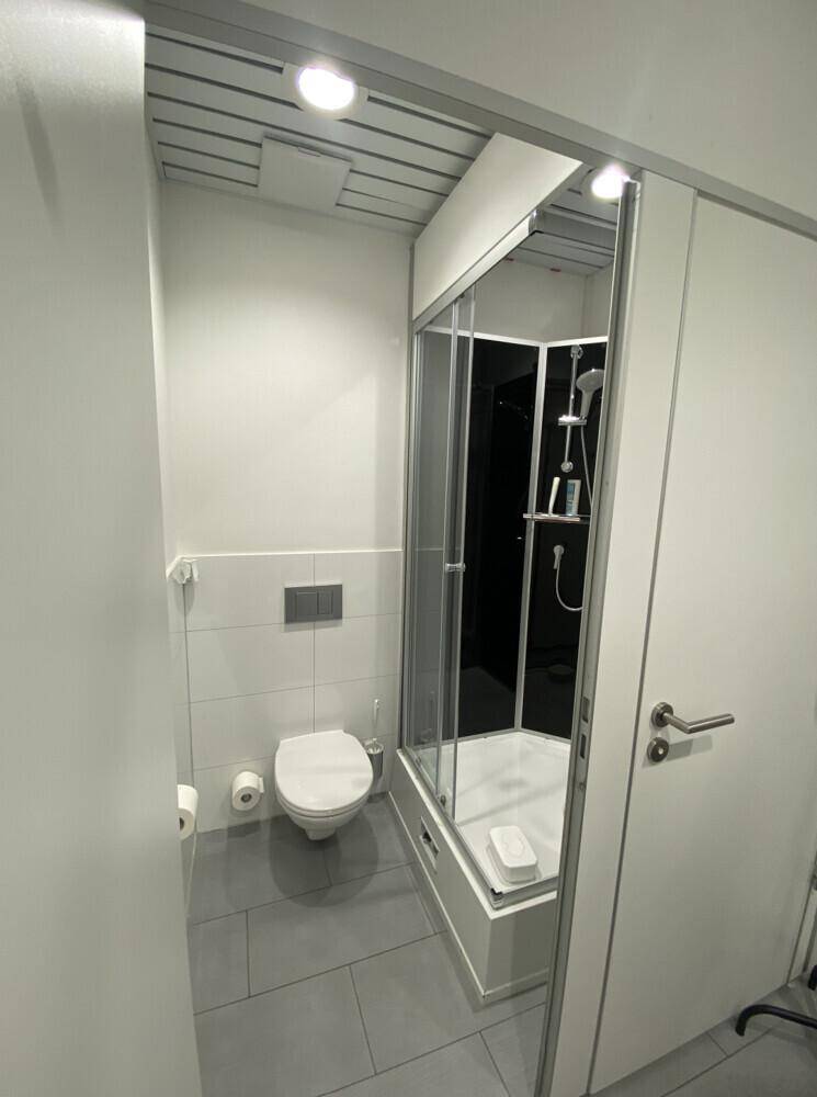 Kompaktes Badezimmer mit moderner Toilette und einer Duschkabine mit Glaswänden.