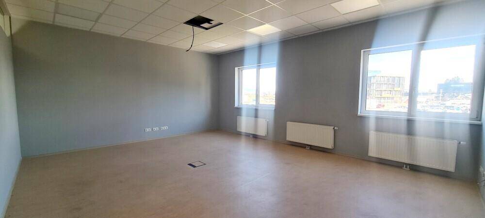 Leerer Büroraum mit zwei Fenstern, Heizkörpern und einer abgehängten Decke, ideal für Arbeitsbereiche.
