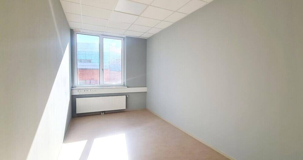 Kleinerer Büroraum mit einem großen Fenster, das viel Licht spendet, und einem Heizkörper darunter.