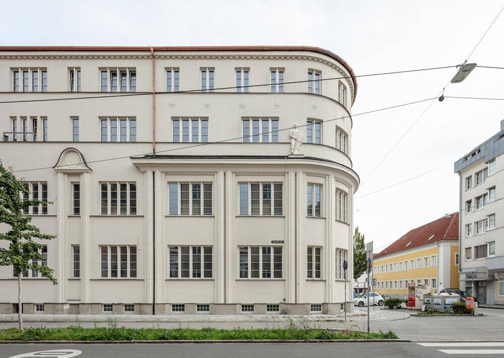 Seitenansicht des Gebäudes mit seiner charakteristischen Rundung und den vielen Fenstern, die auf die Straße blicken.