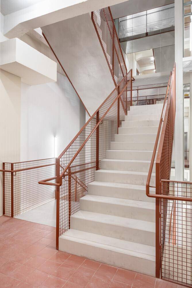 Modernes Treppenhaus mit Betonstufen und robusten Metallgeländern, das verschiedene Etagen miteinander verbindet.