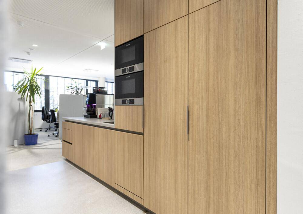 Moderne Teeküche mit Holzschränken, integrierten Geräten und viel Stauraum.
