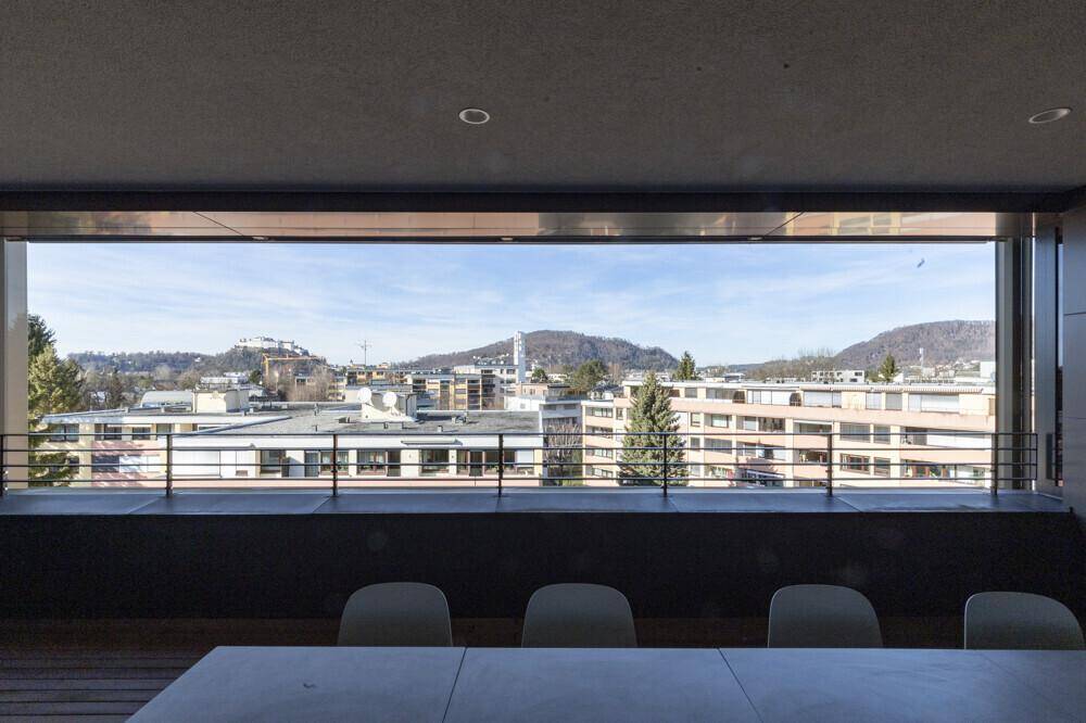 Weitläufiger Balkon mit Panoramablick auf die Stadt und die grüne Landschaft, perfekt für Mahlzeiten im Freien.