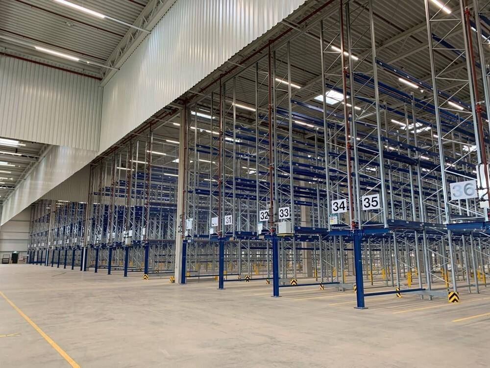 Moderne Lagerhalle mit blauen und silbernen Regalsystemen und heller Beleuchtung.