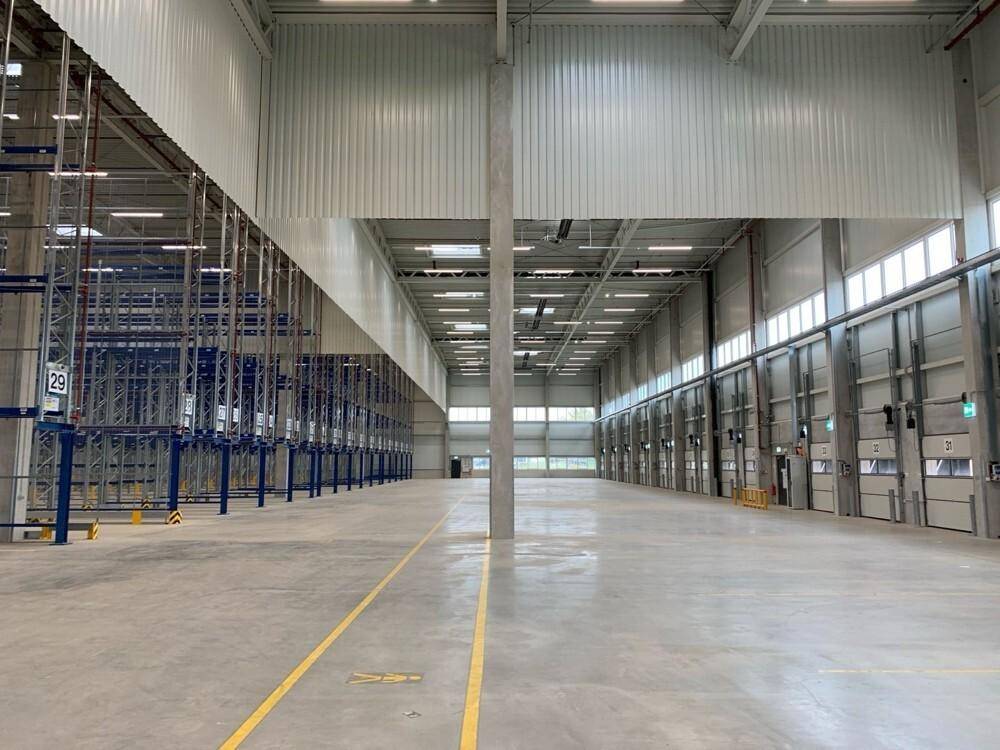 Weitläufige, leere Lagerhalle mit hohen Decken und zahlreichen Rolltoren für den Warenverkehr.