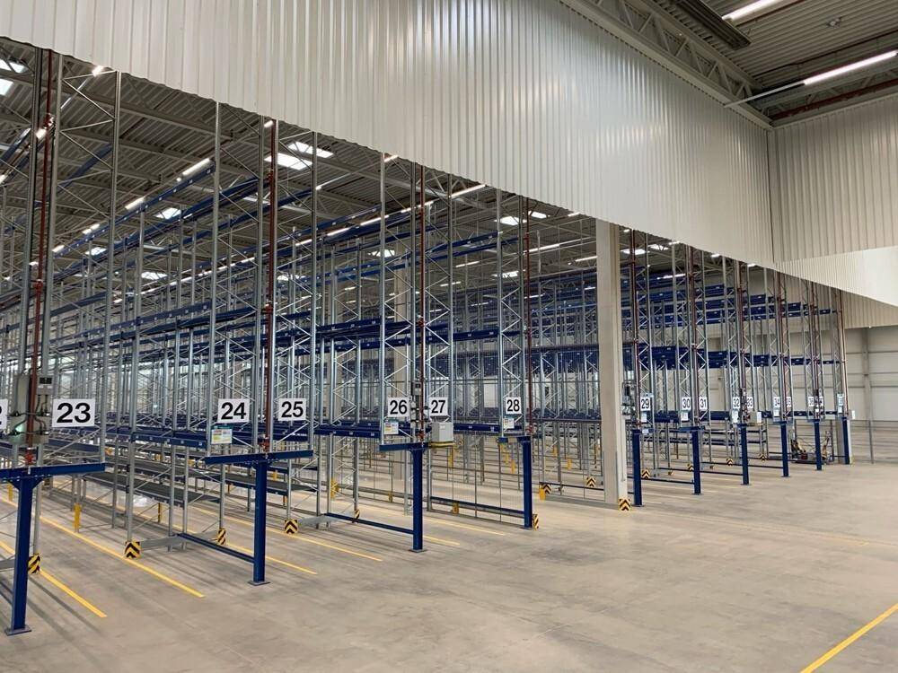 Geräumige Lagerhalle mit umfangreichen Regalsystemen und heller Beleuchtung.