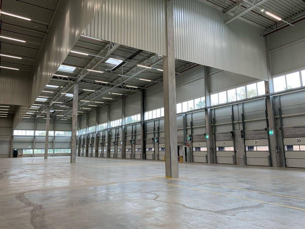 Geräumige Lagerhalle mit einer langen Reihe von Rolltoren und hohen Decken.