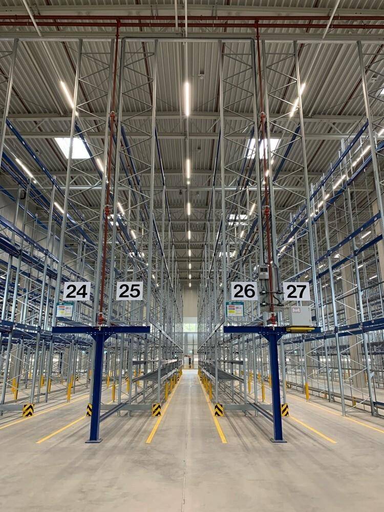 Langer Gang in der Lagerhalle mit hohen Regalen und nummerierten Stellplätzen.