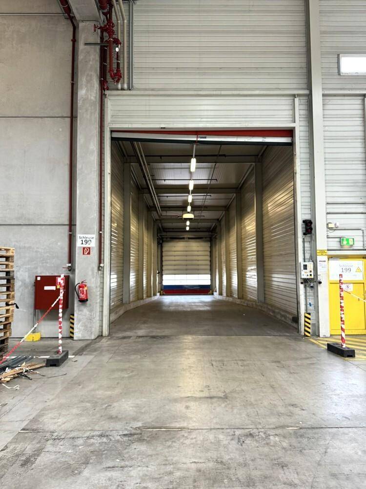 Innenansicht einer Zufahrtsrampe zu einer Lagerhalle mit Rolltor und Beleuchtung.