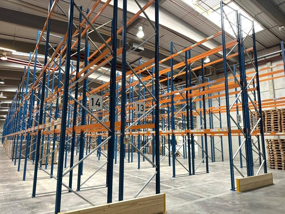Lagerhalle mit hohen Regalsystemen für Palettenlagerung und Betonboden.