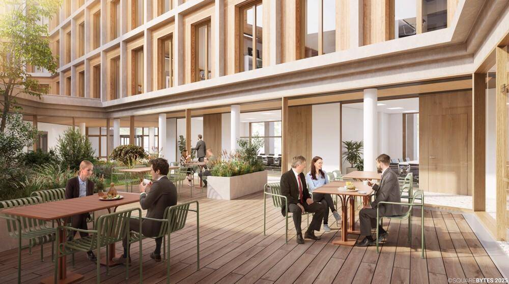 Begrünter Innenhof mit Sitzgelegenheiten und Tischen, ideal für Pausen und Treffen.