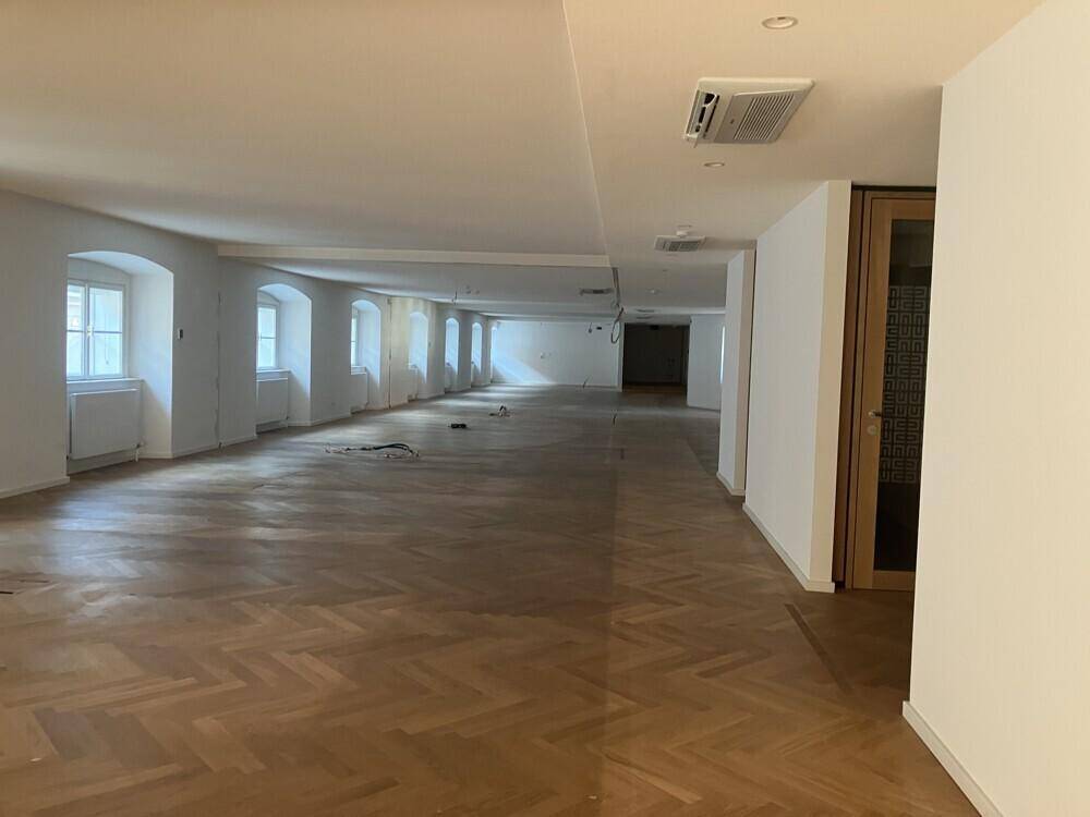 Langer, heller Büroraum mit vielen Fenstern und elegantem Fischgrätparkett.