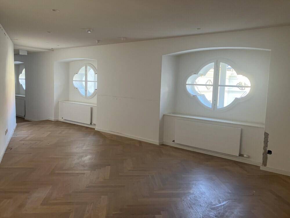Heller Büroraum mit einzigartigen, runden Fenstern und Heizkörpern unter den Nischen.