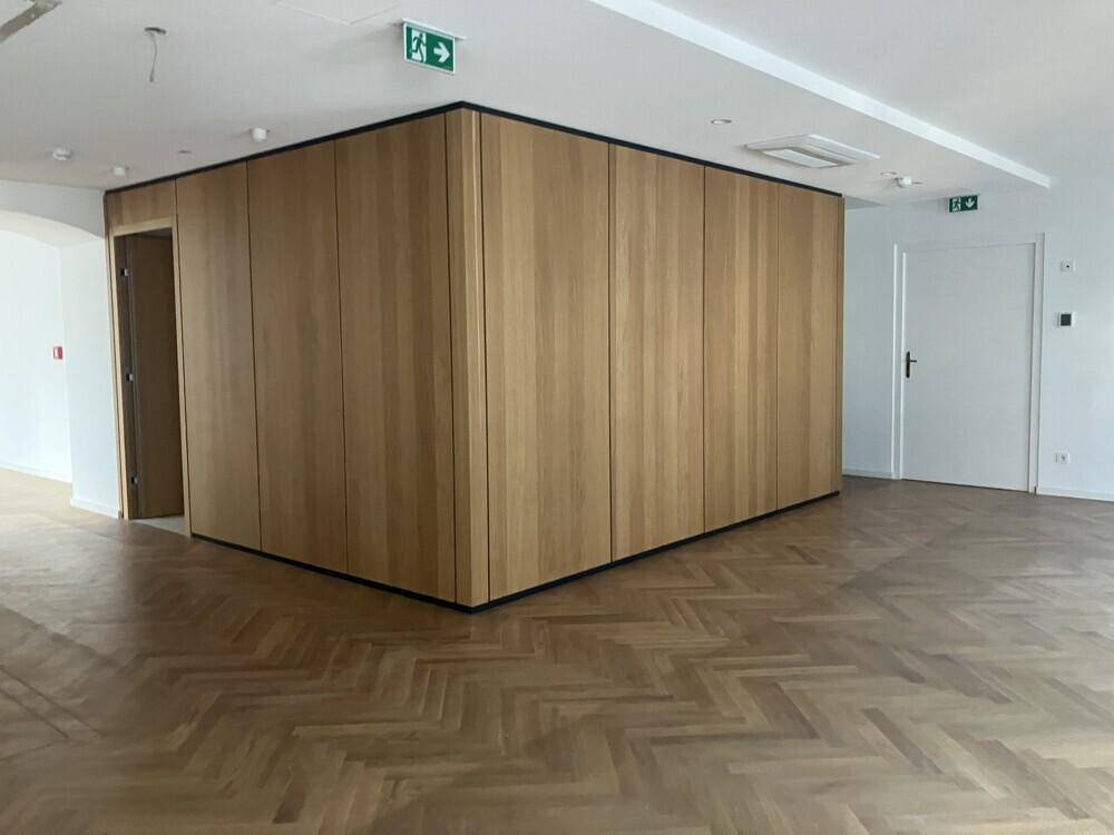 Großer Büroraum mit modernem Holzpaneel-Element und klassischem Fischgrätparkett.