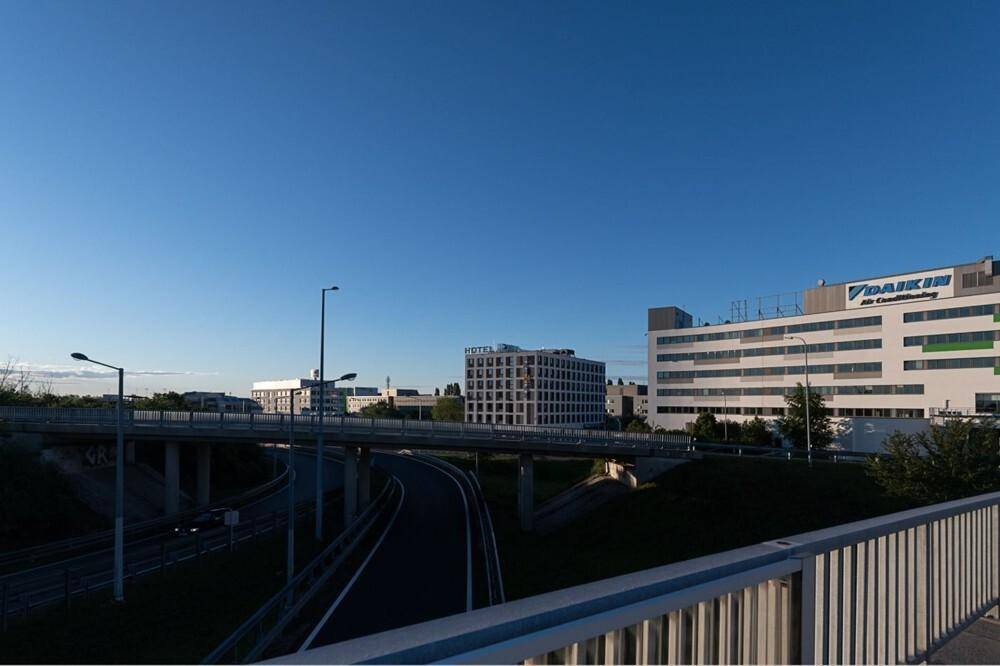 Blick auf moderne Bürogebäude und eine Überführung unter klarem, blauem Himmel.