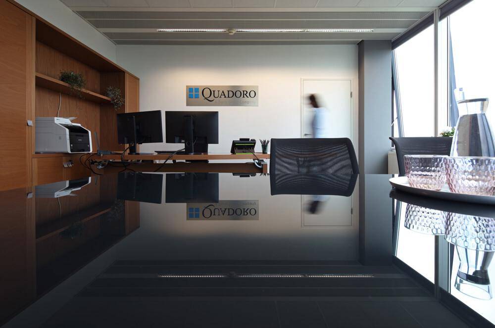 Modernes Büro mit glänzendem schwarzen Tisch, Holzregalen und Blick auf den Arbeitsbereich.