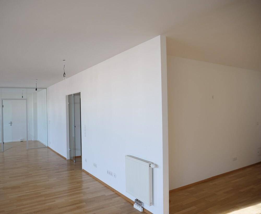Geräumiger, heller Innenraum mit Holzboden und einer weißen Trennwand, die den Raum strukturiert.