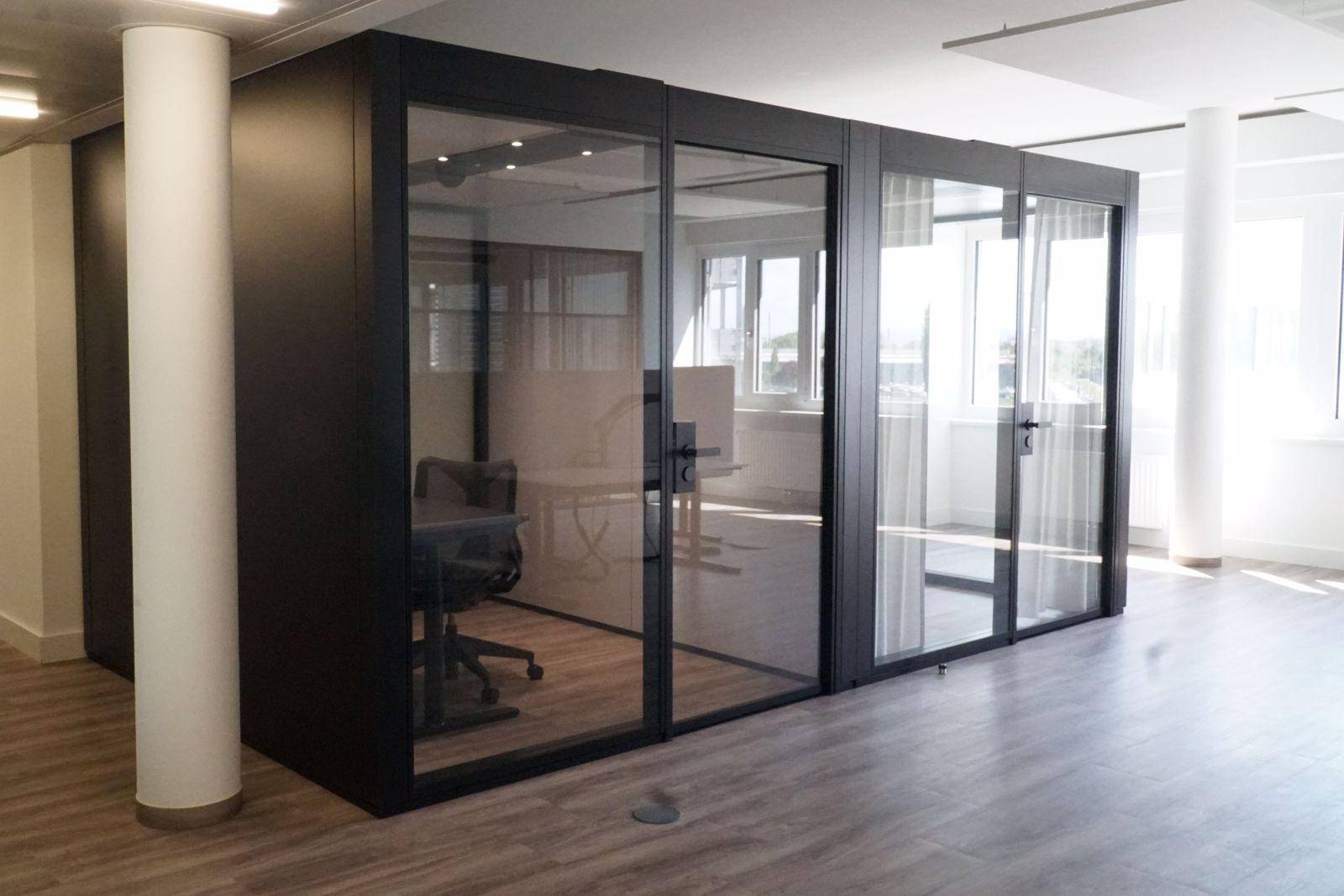 Moderne Büroräume mit schallgedämmten Glasboxen für private Arbeitsbereiche und Besprechungen.