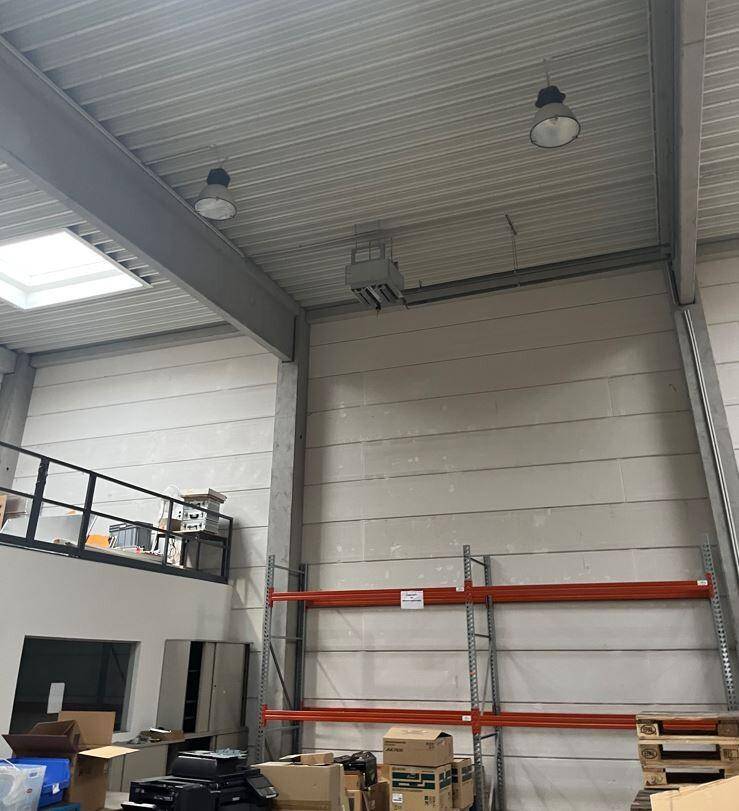 Hohe Decken und Wände einer Lagerhalle mit Metallträgern und einem Oberlicht.