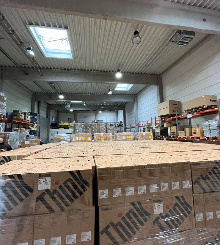 Großes Lager mit hohen Decken, Oberlichtern und Regalen voller verpackter Produkte.
