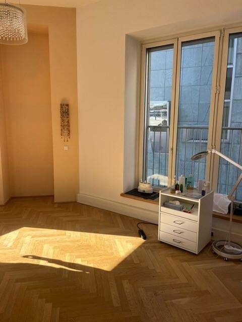Heller Raum mit Fischgrätparkett und großem Fenster, durchflutet von natürlichem Sonnenlicht, ideal als Büro.