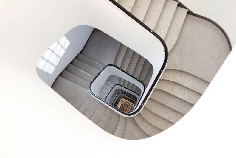 Elegante Wendeltreppe in einem modernen Gebäude, von oben fotografiert, mit viel Tageslicht und klaren Linien.