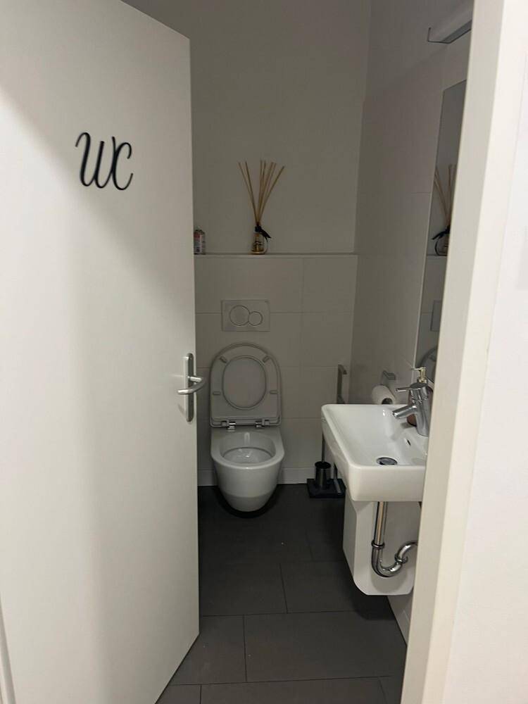 Modernes Gäste-WC mit wandhängender Toilette und kleinem Waschbecken, in schlichtem Design und hellen Fliesen.