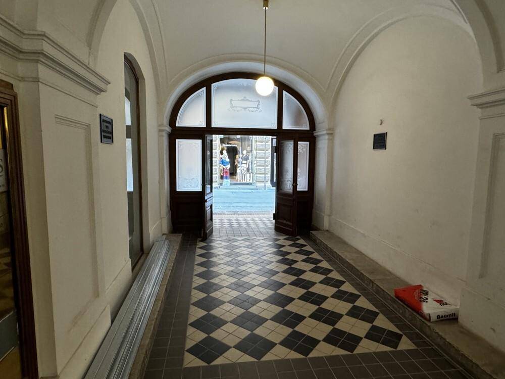 Heller Eingangsbereich mit gewölbter Decke und schwarz-weiß kariertem Fliesenboden.